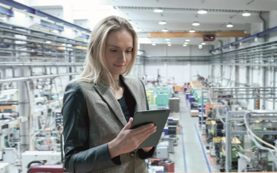 A woman in a factory using a tablet to monitor production processes and manage data efficiently.