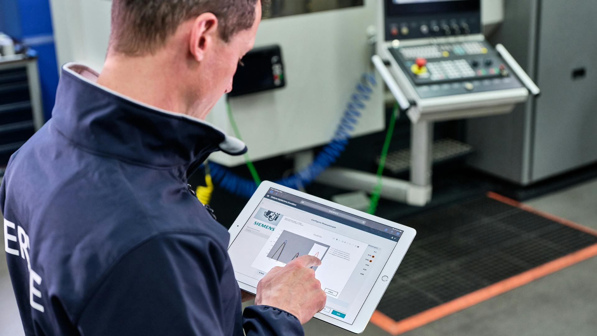 A service engineer uses a tablet with Salesforce and Siemens software to perform maintenance on a machine.