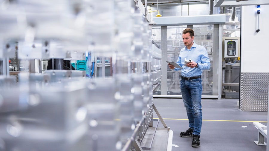 A man standing in a medical device facility holding a tablet.