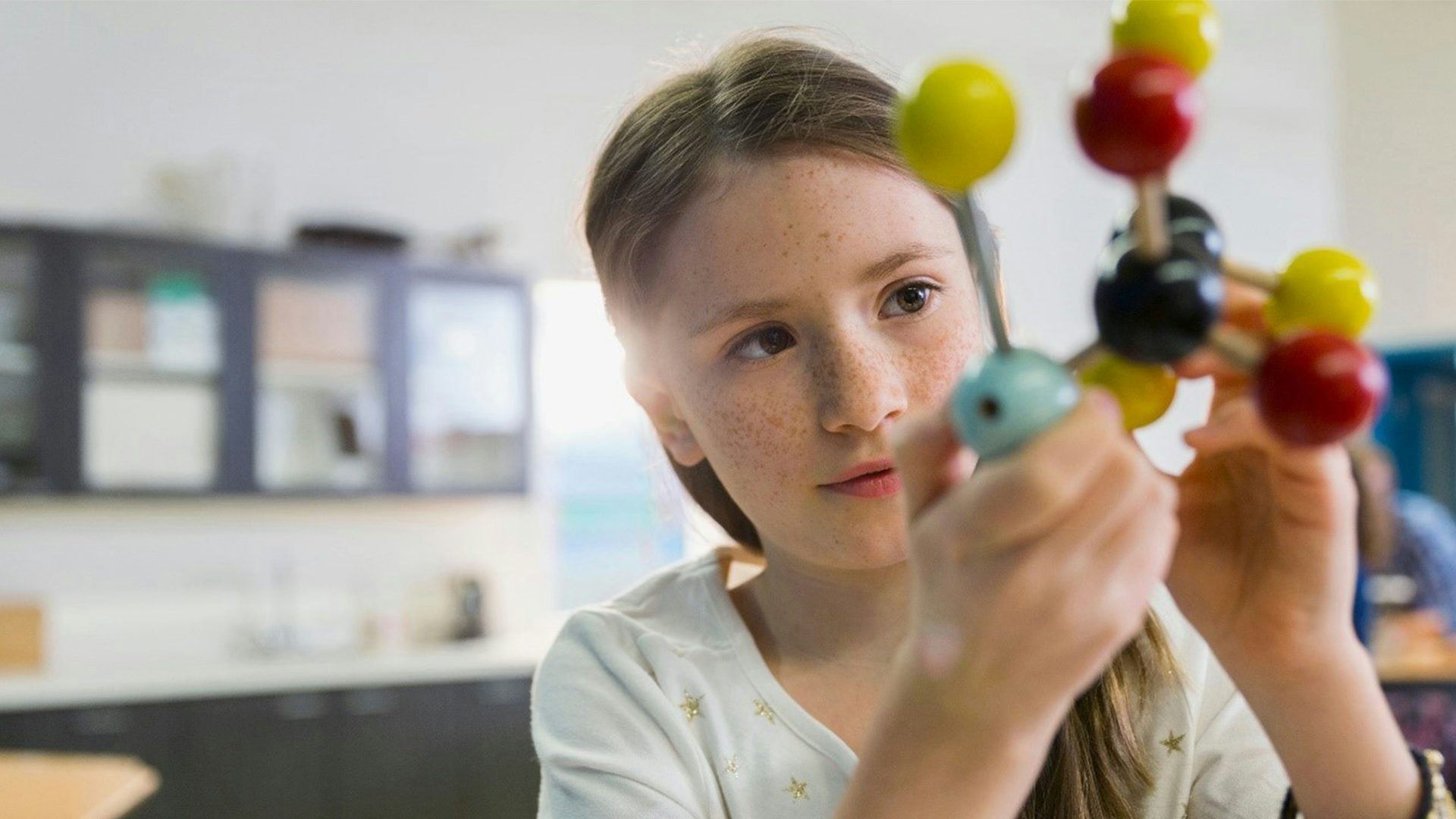 Ein Kind untersucht ein Modell eines komplexen Atoms.