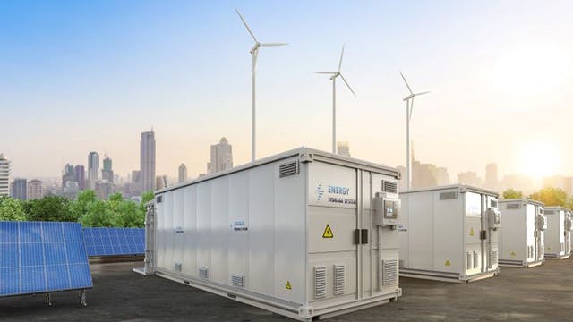 Solar panels and a battery energy storage system with a city skyline in the background during daylight.