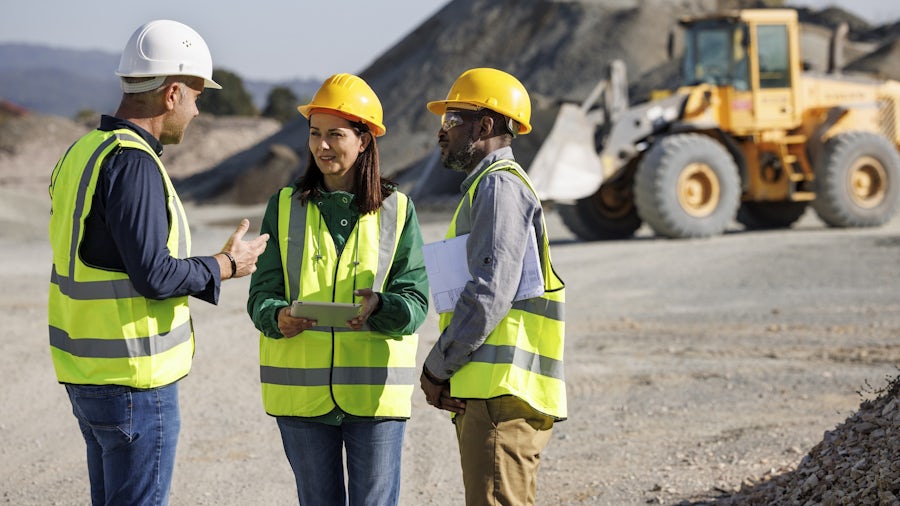 3 lavoratori che usano attrezzature pesanti discutono di una BOM