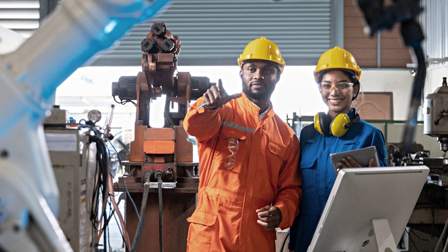 Zwei Ingenieure in einer Fabrikhalle besprechen einen Serviceplan für eine Industriemaschine.
