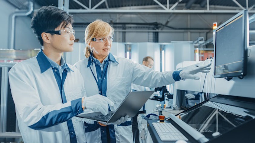 Two semiconductor manufacturing employees working in a factory.