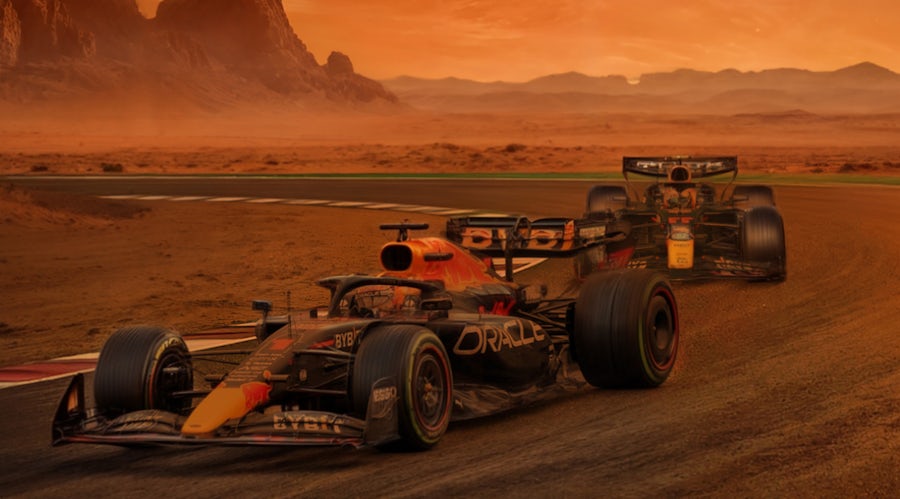 Two racing cars compete on a sunlit desert track, kicking up dust as they race.