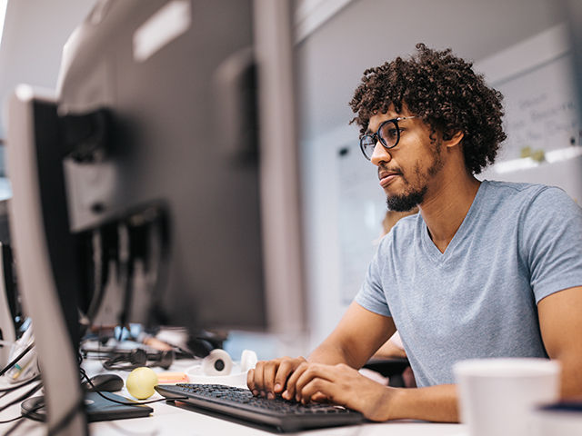 パソコンの前に座り、モニターを見つめる男