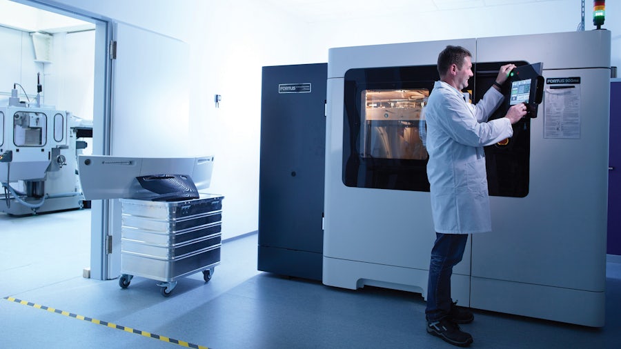Operario que utiliza herramientas digitales de producción de piezas para fabricar piezas mecánicas con una máquina CNC.