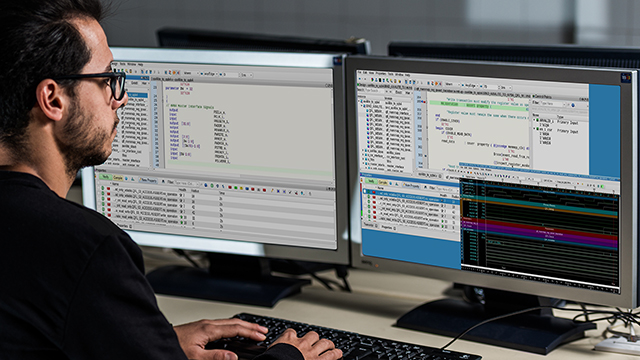 An engineer uses Questa Check Register Tool on his two monitors.