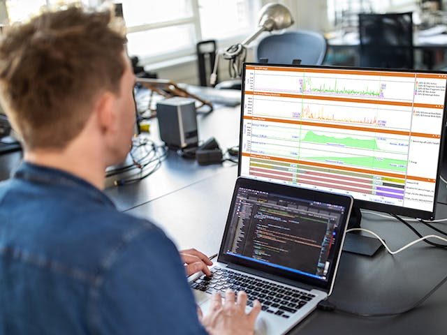 An engineer analyzing software application code while viewing a waveform simulation graph from the CodeBench product.