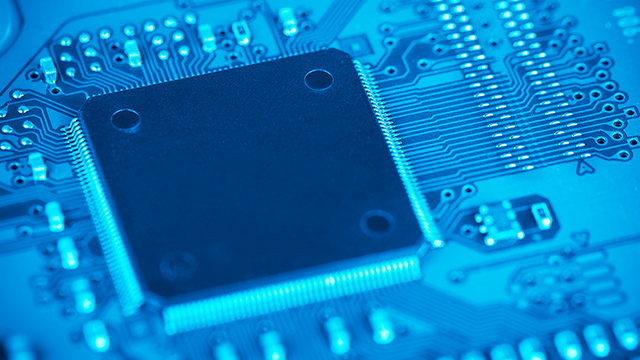 Close-up view of an electronic chip mounted on a blue circuit board.