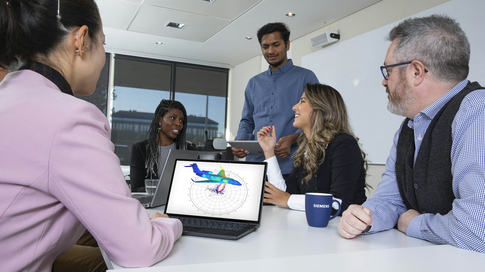 Group of people looking at high-frequency electromagnetics simulation on a screen.