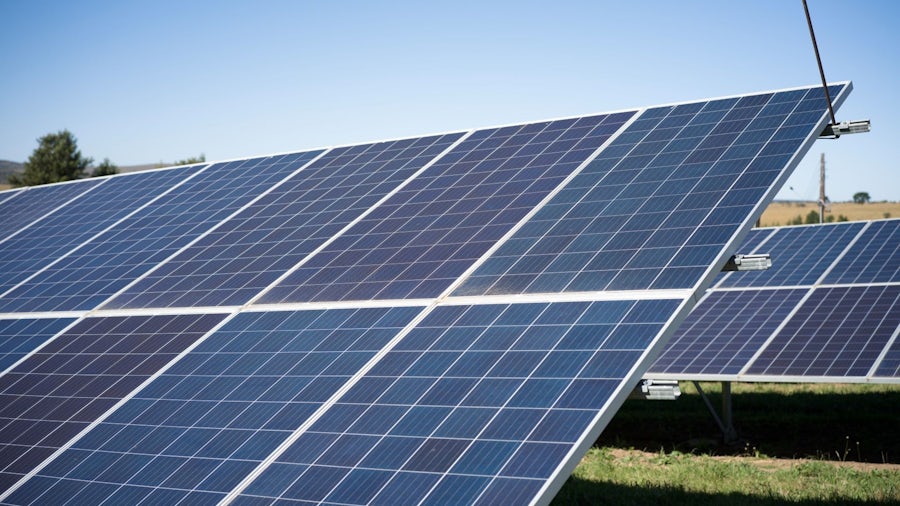 Solar panels on a rural farm, set against a backdrop of open fields and blue skies.