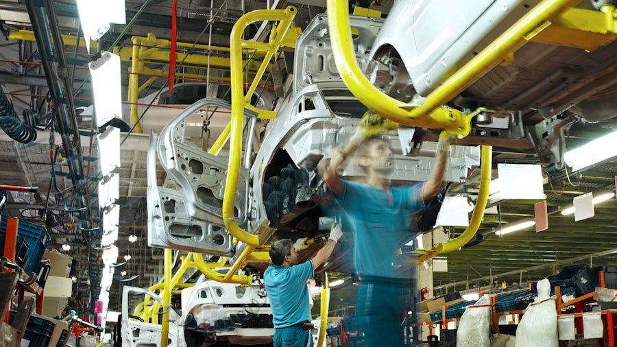 Assembly line workers working on next generation vehicle on an automotive assembly line.