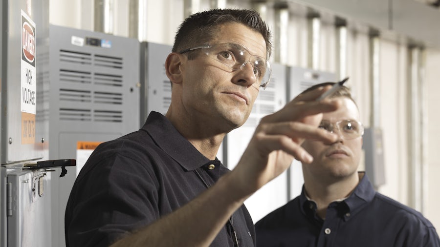 Two service engineers look at what needs to be done to maintain an industrial machine.