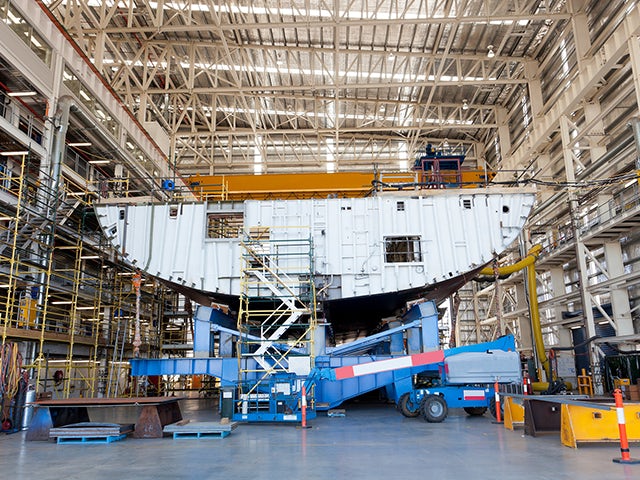 Une coque de navire en construction à l’intérieur d’un bâtiment d’un chantier naval