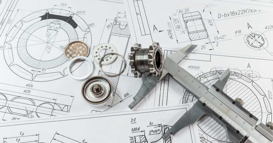 CAD drawings on a table with physical tools and parts