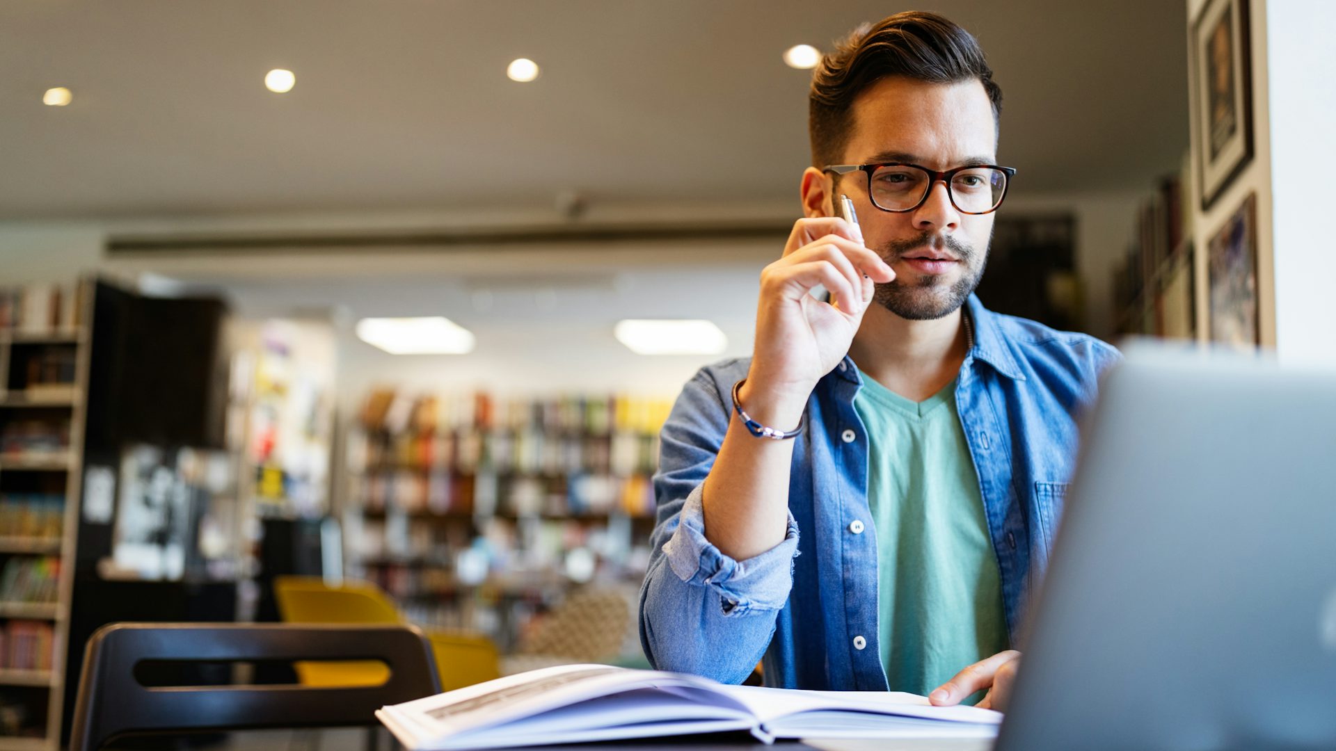 Man in a library looking at laptop