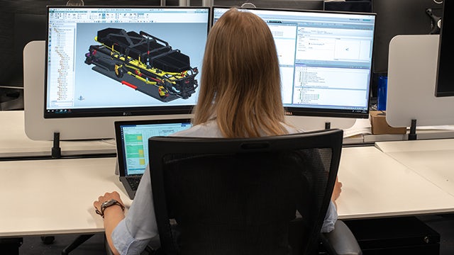 A woman works at a computer displaying Siemens CAD software
