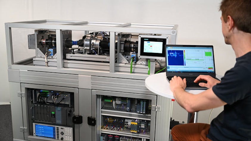 Mechatronic systems testing and analysis being performed by an engineer using advanced test bench with dual monitors and control equipment.