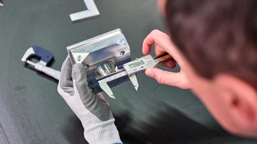 Un fabricante mide la pieza de una máquina para asegurar que el producto cumple las normas de calidad.