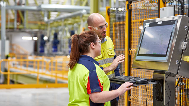 Two engineers are checking desktop mentor in a factory