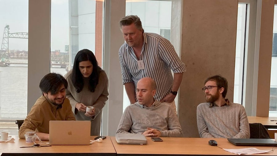 Workshop participants looking at a laptop with solution in a meeting room.