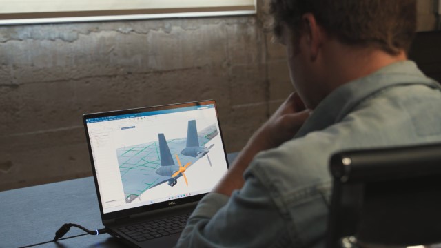 A Natilus design engineer working on the widebody plane design in NX CAD on his laptop.