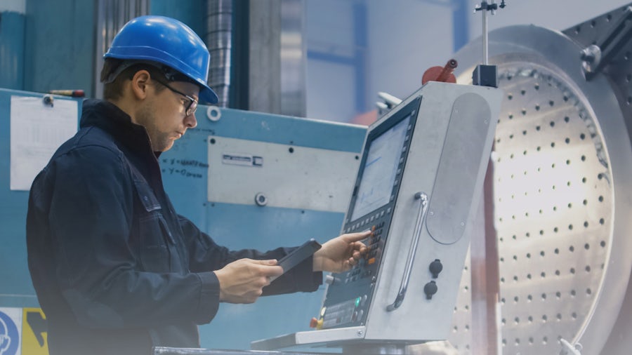 Un ingegnere addetto alla gestione della qualità ispeziona una macchina industriale.