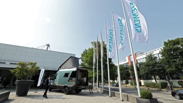 Hymer truck outside a conference center with white Siemens flags blowing in the wind.