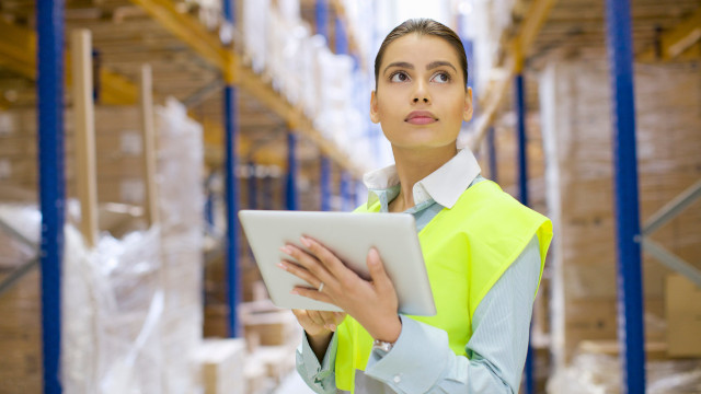 Woman in a warehouse holding a tablet.