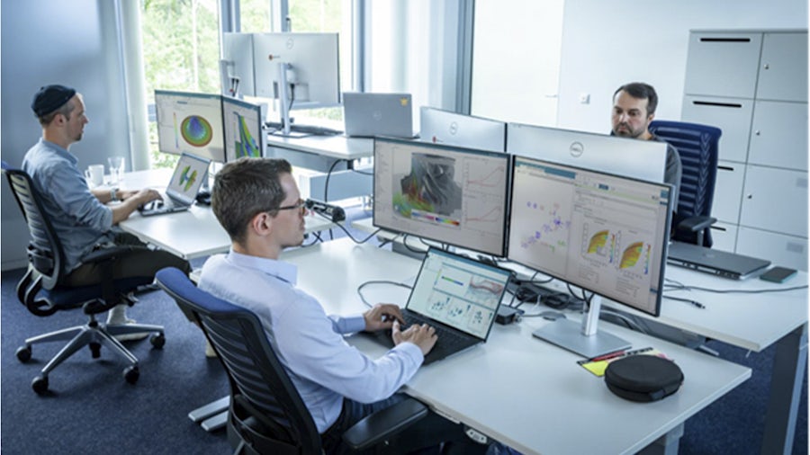 Engineers working at desks with multiple monitors displaying simulation data and advanced visualizations, representing Simcenter X Advanced in a modern engineering environment.