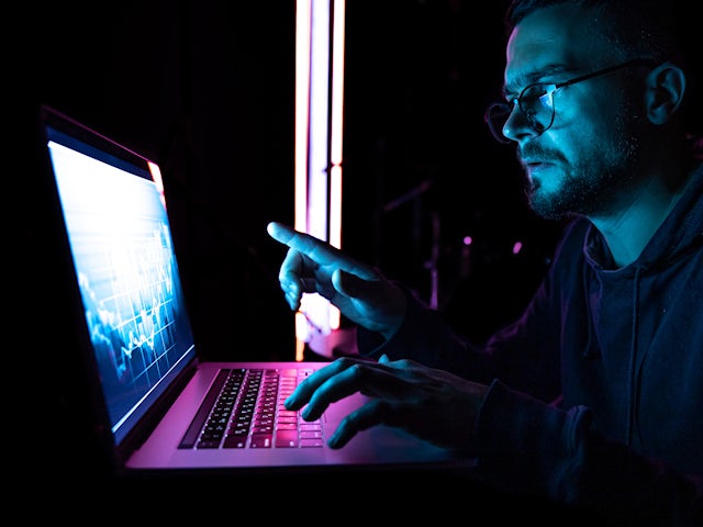 A man analyzing a multitude of data on a laptop.