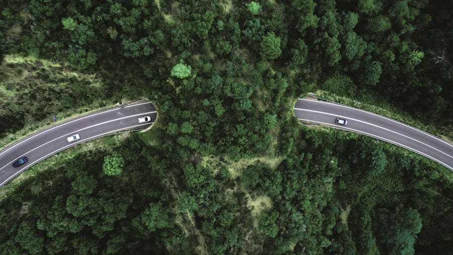 Aerial view of four cars driving on a highway in the mountains.