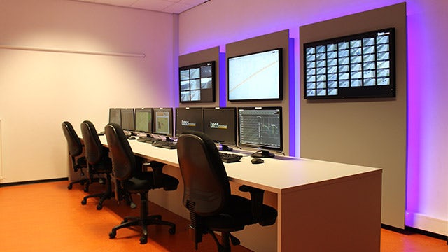 A control room operations center with chairs, computer terminals and video screens.