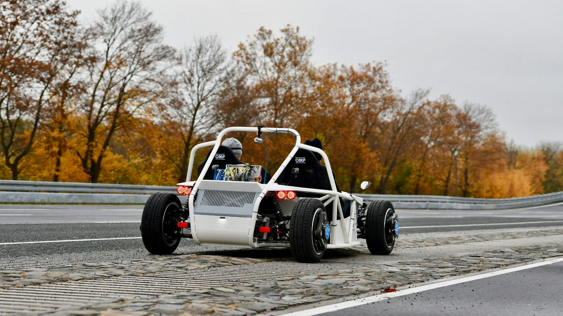 An open-topped car driving on an empty road