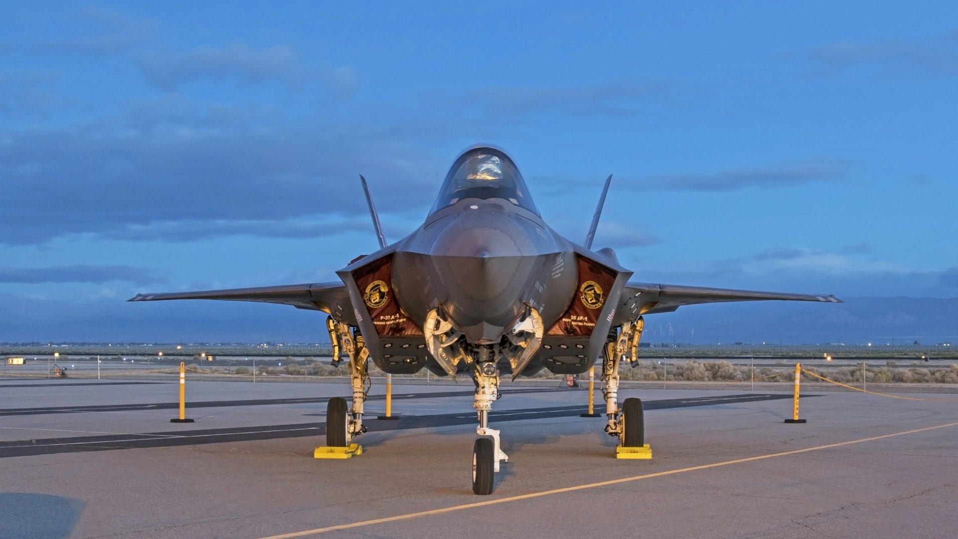 An F-35 Lightning sits on a runway at sunrise.