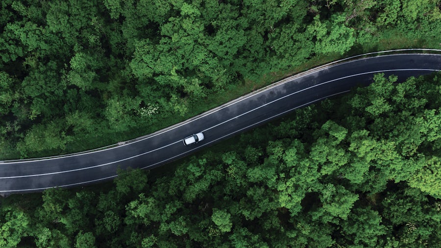 Modern vehicle shown driving down a highway with green environmental surroundings