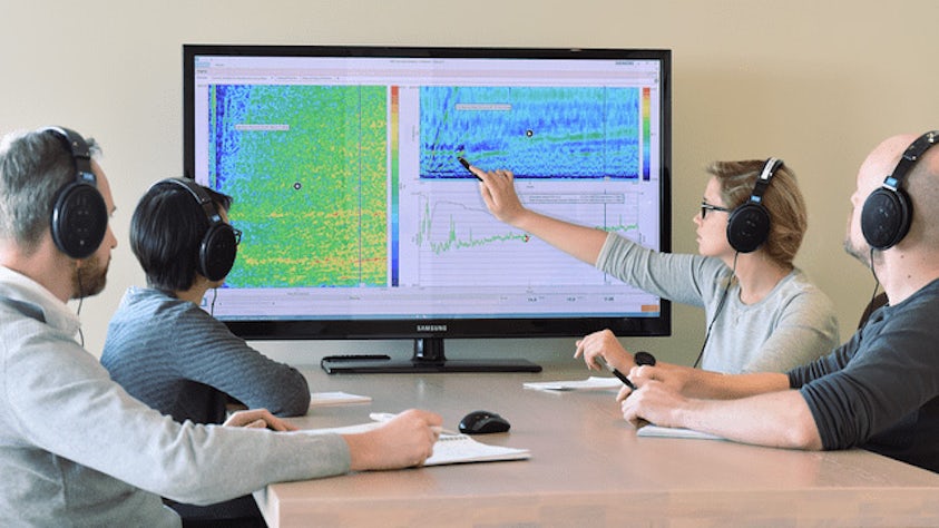 Group of people looking at the Simcenter acoustic testing tool on screen.