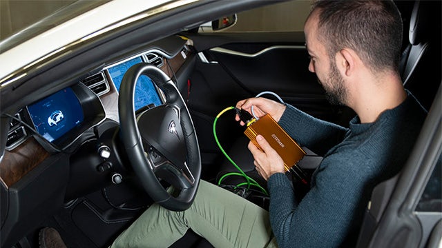 An engineer using a Simcenter device runs an active sound test inside the car.