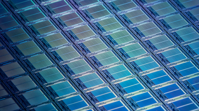 close up view of iridescent blue IC dies on a segment of a silicon wafer