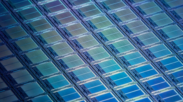 close up view of iridescent blue IC dies on a segment of a silicon wafer
