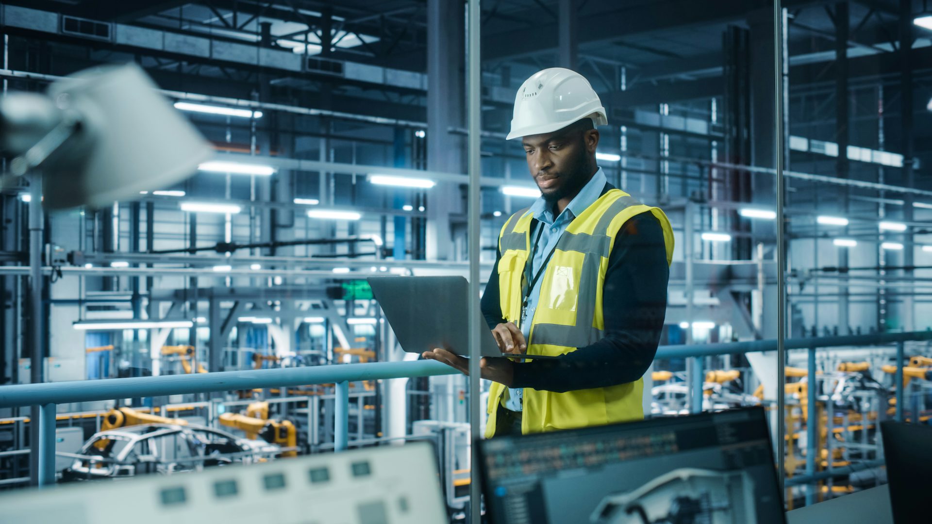 Man in a car plant holding a device