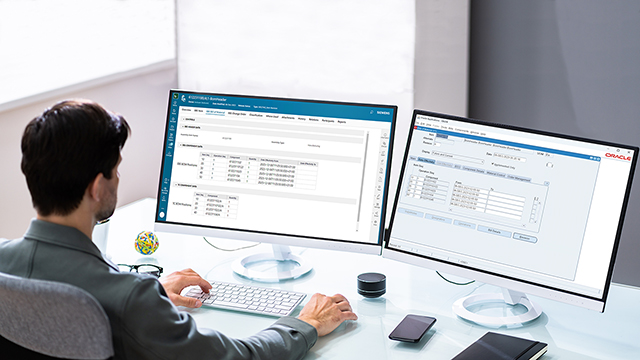 Uomo seduto a una scrivania davanti a un doppio monitor.