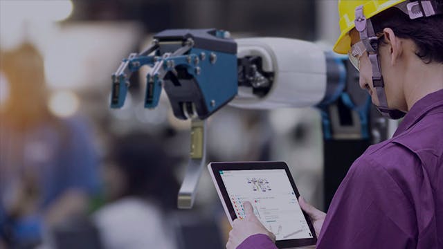 Engineer working with a tablet to control a robotic arm.