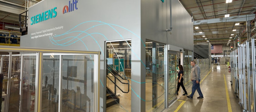 The image shows a glass-walled industrial area branded with SIEMENS and alit, featuring the message 