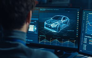 A man views a display of an automotive design on his computer monitor.
