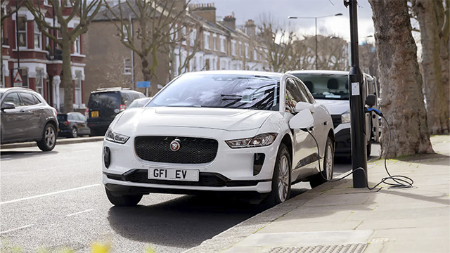 Samochód elektryczny zaparkowany na ulicy podczas ładowania.