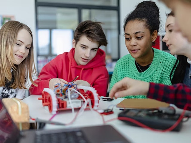 Mutiple students working with a model of small device prototype.