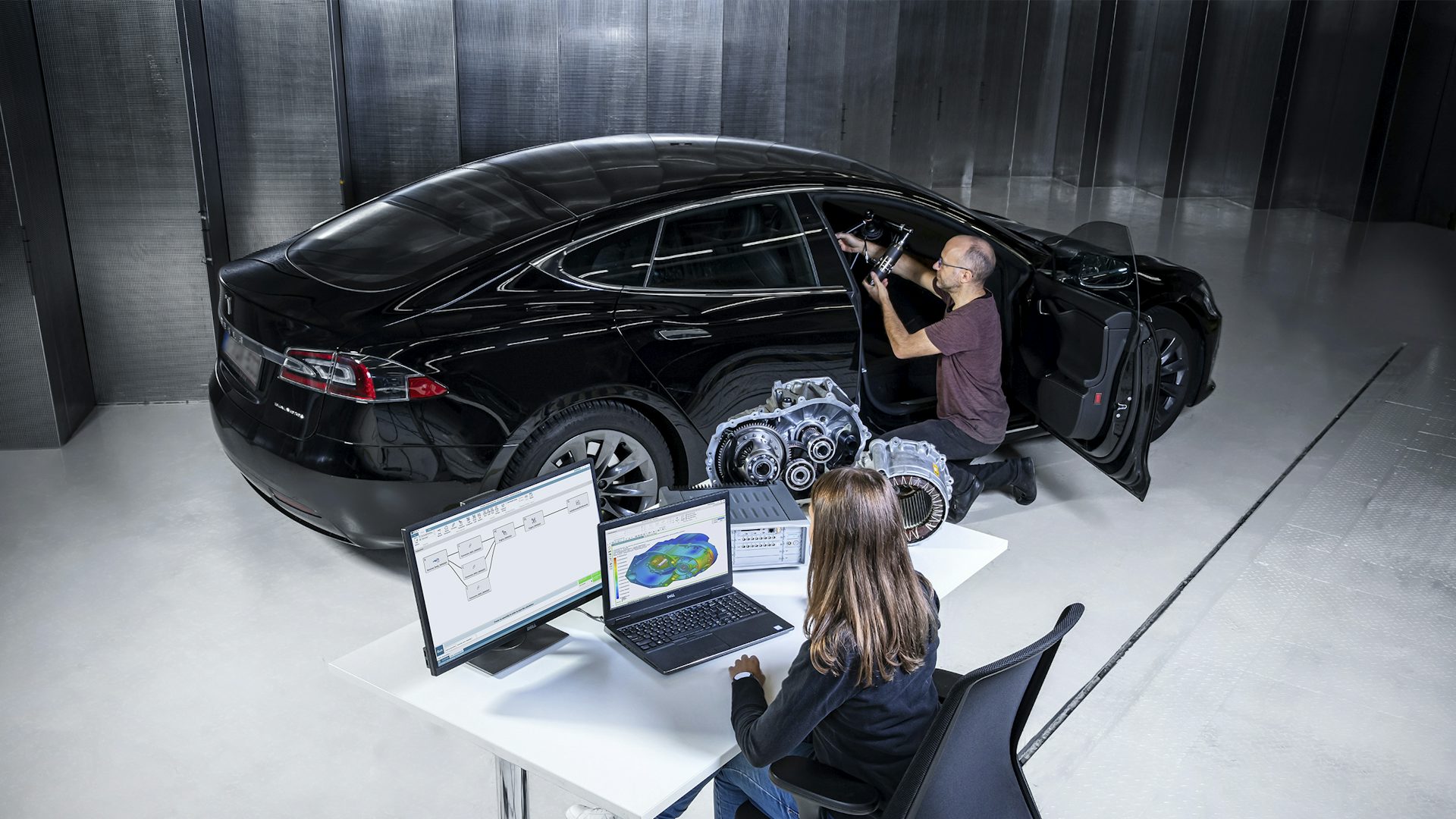 Two people using System NVH performance prediction software on a car.
