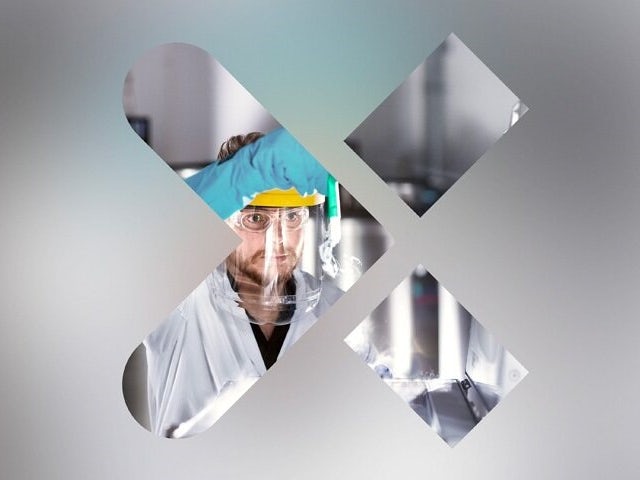 Muž v bílém laboratorním plášti a s obličejovým štítem uvnitř loga Siemens Xcelerator